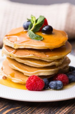 Böğürtlenli krep, ahududu ve ahşap zemin üzerinde akçaağaç pekmezi. Kahvaltı ve geleneksel yemek..