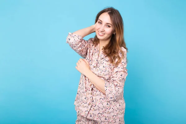 Young girl posing in pajamas on blue background. Relax good mood, lifestyle and sleepwear concept. — Stock Photo, Image