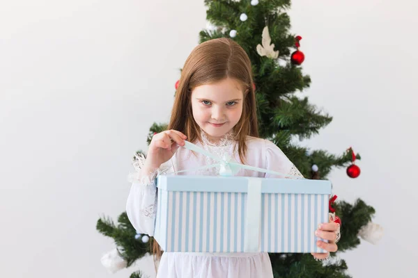 Mädchen öffnet Geschenkbox neben Weihnachtsbaum Feiertage, Weihnachten und Geschenke. — Stockfoto