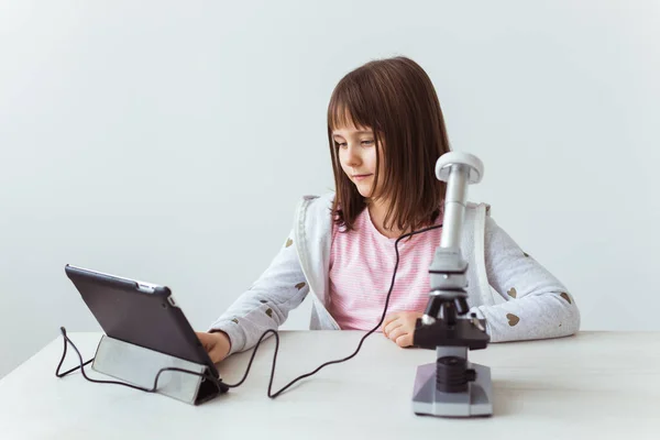 Colegiala usando microscopio en clase de ciencias. Tecnologías, lecciones y concepto infantil . —  Fotos de Stock