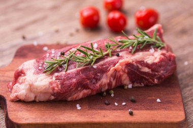 Çiğ et. Biberiye ve baharatla ahşap kesim tahtasına sığır pirzolası..