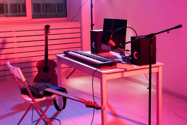 Microfono, computer e attrezzature musicali chitarre e pianoforte sfondo. Home studio di registrazione concetto . — Foto Stock