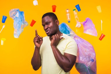 Çöp, plastik geri dönüşüm, kirlilik ve çevre konsepti sorunu - geri dönüşüm için çöp taşıyan Afro-Amerikan adam ve sarı arka planda işaret.