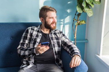Teknoloji ve eğlence konsepti. Evde akıllı telefon kullanan yakışıklı bir adam..