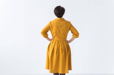 Giysi, tasarımcı, insan konsepti. Sarı elbiseli çekici bir kadının arka görünüşü. Beyaz odada fotokopi alanı ile poz vermesi..