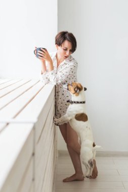 Sakin ve rahat. Evinin penceresinin yanında duran bir fincan çay ve köpekle güzel genç bir kadın.