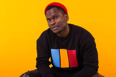 Afro saçlı, yakışıklı Afrikalı Amerikalı bir adam. Sarı arka planda bir portre. Kameraya bakan adam..