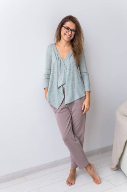 Güzel renkli pijama giymiş, oturma odasında model kılığına girmiş çekici bir kadın. Rahat uyku giysileri, ev rahatlığı ve kadın moda konsepti..
