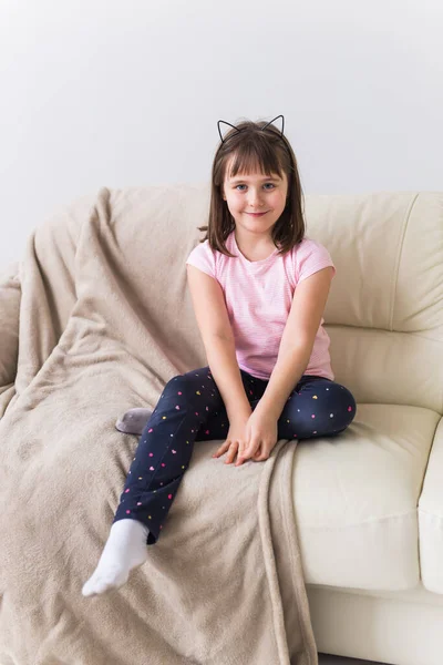 Schattig meisje met kattenoren op de bank. Begrip kinderen en jeugd. — Stockfoto