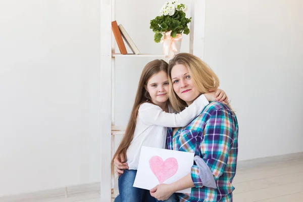 Šťastný Den matek. Dcera gratuluje mámě a dává jí pohlednici. Máma s holkou se usmívají a objímají. Rodinná dovolená a mateřství. — Stock fotografie