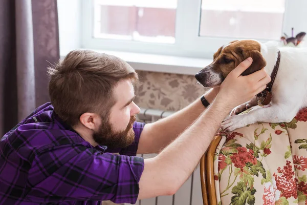 Feliz joven sentado con su perro en casa. Propietario de mascotas, animales y concepto de amistad . — Foto de Stock