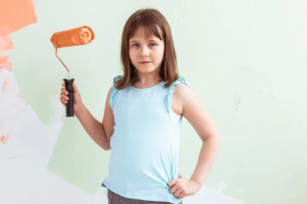 Elinde boya silindiri olan bir çocuk. O, duvarı boyuyor. Dekorasyon, onarım ve yeniden boyama kavramı. — Stok fotoğraf