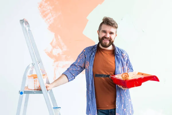 Happy man painting wall in her new apartment. Renovation, redecoration and repair concept. — Stock Photo, Image