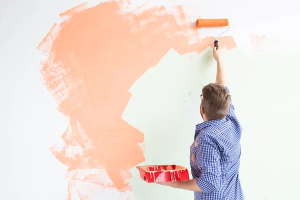 Riparazione nell'appartamento. L'uomo dipinge il muro con la vernice. Vista posteriore. Copia spazio — Foto Stock