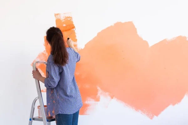 Yeni evin duvarlarını boyayan neşeli bir kadın. Yenileme, onarım ve dekorasyon konsepti. Boşluğu kopyala. — Stok fotoğraf