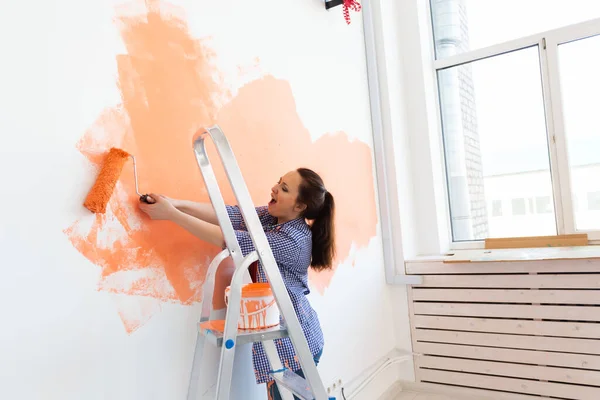 Renovación, redecoración y concepto de reparación - Alegre pared de pintura de mujer en un nuevo hogar. — Foto de Stock