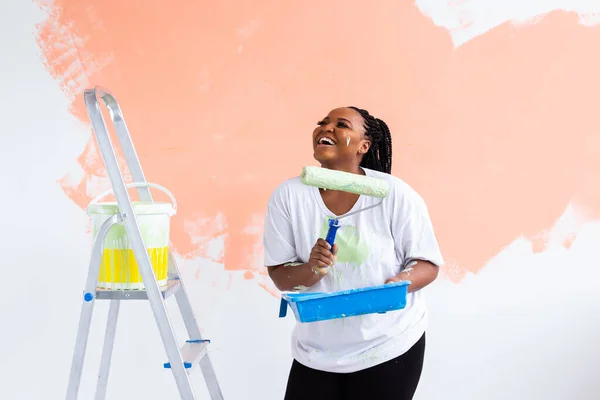 Riparazione nell'appartamento. Giovane donna felice dipinge il muro con vernice . — Foto Stock