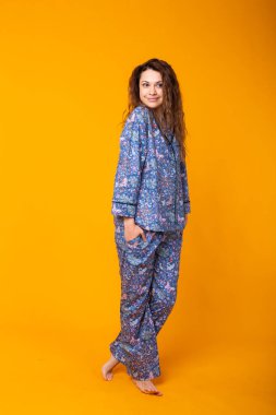 Mavi elbiseli genç bayanı kapatın. Sarı arka planda izole edilmiş. Pijama konsepti.