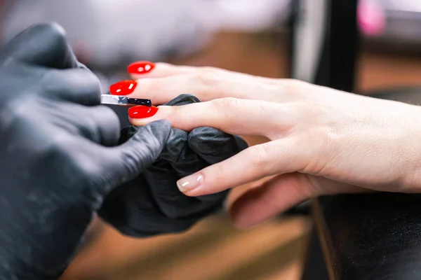 Close Up shot of master in rubber gloves covering red nails with top coat in the beauty salon. Perfect nails manicure process. — Stock Photo, Image