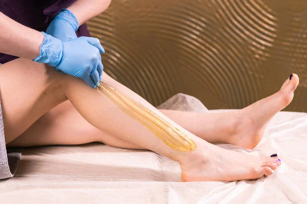 Женщина, проходящая процедуру удаления волос на ноге с сахарной пастой в салоне крупным планом. Концепция косметологии . — стоковое фото