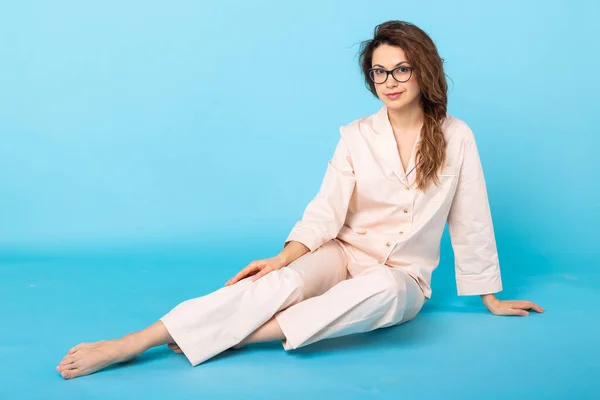 Junges Mädchen posiert im Schlafanzug auf blauem Hintergrund. Gute Laune, Lifestyle- und Schlafbekleidungskonzept. — Stockfoto