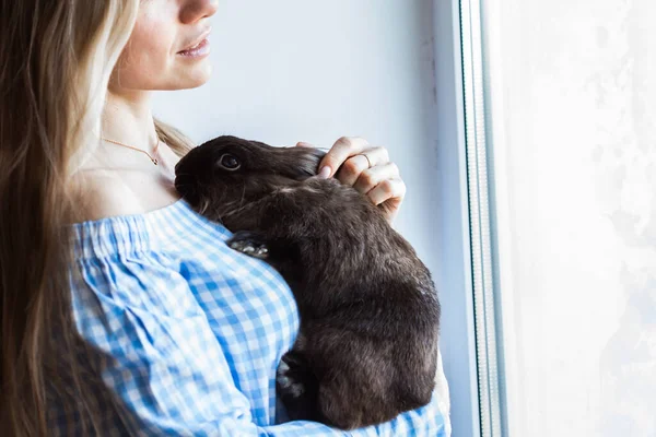 Mascotas y concepto de Pascua - Chica feliz abrazando conejo marrón en casa . — Foto de Stock