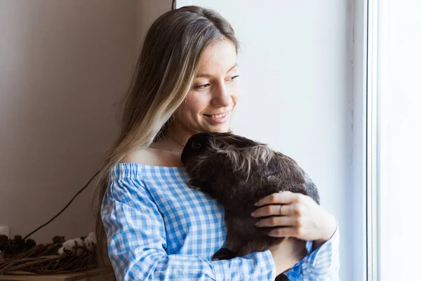 Pet och påsk koncept - Glad flicka kramar brun kanin hemma. — Stockfoto