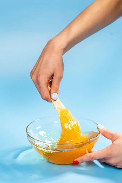 Flytande gul pasta för socker på blå bakgrund. Hårborttagning och hårborttagning. — Stockfoto