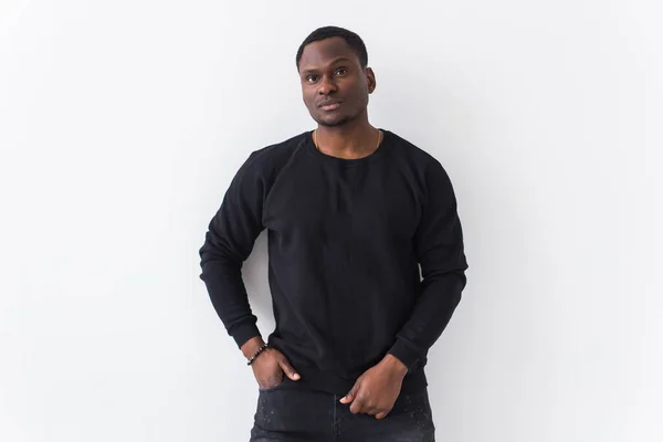 Portrait handsome young black man dressed in jeans and sweatshirt on white background. Street fashion and modern youth culture. — Stock Photo, Image