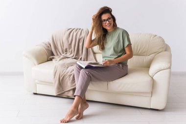 Güzel kız kitap okuyor. Rahatlama, yavaş yaşam, hobi, ev konforu kavramı. Sosyal medya, dijital detoks. Karantina, kendini izole etme, sosyal fobi.