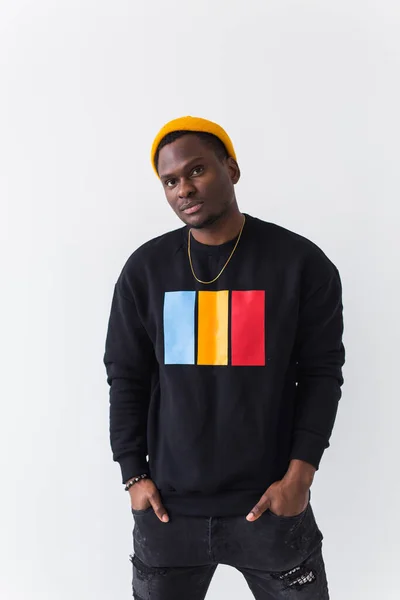 Portrait handsome young black man dressed in jeans and sweatshirt on white background. Street fashion and modern youth culture. — Stock Photo, Image