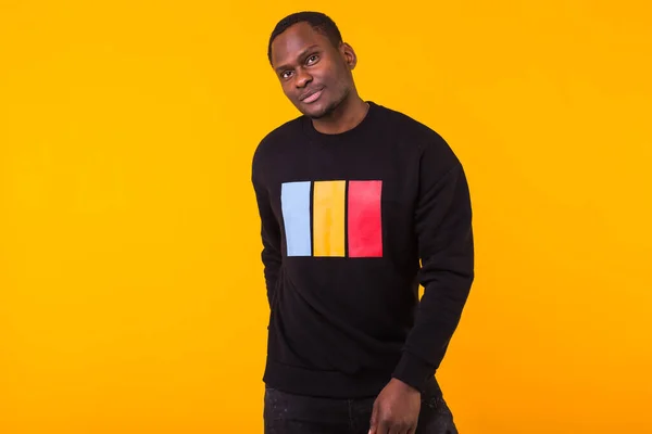 Street fashion concept - Studio shot of young handsome African man wearing sweatshirt against yellow background. — Stock Photo, Image