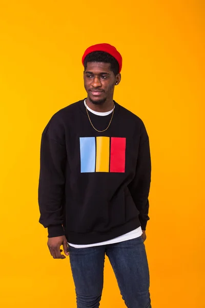 Street fashion concept - Studio shot van jonge knappe Afrikaanse man draagt sweatshirt tegen gele achtergrond. — Stockfoto