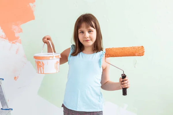 Ragazzo in piedi con il rullo di vernice in mano. Sta dipingendo il muro. Ridecorazione, riparazione e riverniciatura concetto . — Foto Stock