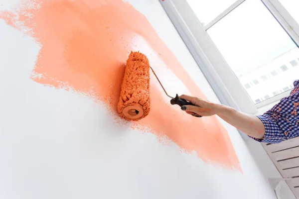 Primo piano di donna pittura parete interna con rullo di vernice in nuova casa. Una donna con rullo che applica vernice su un muro . — Foto Stock
