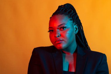 Güzel, genç bir Afrikalı kadın karanlık bir arkaplanda poz veriyor..