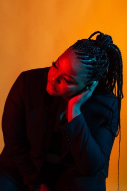 Güzel, genç bir Afrikalı kadın karanlık bir arkaplanda poz veriyor..