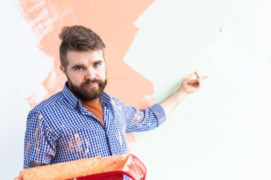 Üzgün adam yeni evin iç duvarını boyuyor. Dekorasyon, yenileme, apartman onarımı ve ferahlatıcı konsept.
