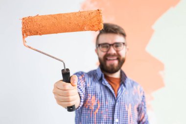 Yeni dairesinde duvar boyayan komik bir adam. Yenileme, dekorasyon ve onarım konsepti.
