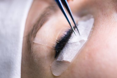 Kirpik uzatma prosedürü. Uzun kirpikli kadın gözü. Kırbaçlar, kapatın, makro, seçici odaklanma.