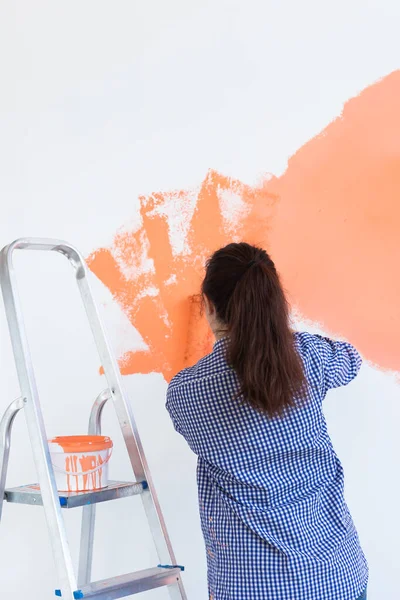 Bella giovane donna con rullo pittura all'interno. Ristrutturazione, ristrutturazione, riparazione di appartamenti e concetto di ristoro. — Foto Stock