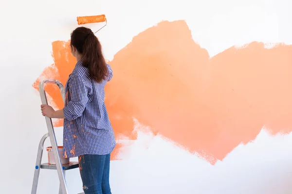 Bella donna pittura muro nel suo nuovo appartamento. Concetto di ristrutturazione e ridecorazione. Copia spazio. — Foto Stock