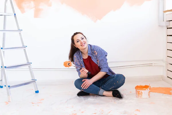 Happy young woman painting wall in her new apartment. Renovation, redecoration and repair concept. — Stock Photo, Image