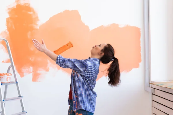 Dansen grappige vrouw schilderen interieur muur van huis met verf roller. Herinrichting, renovatie, appartement reparatie en verfrissing concept. — Stockfoto