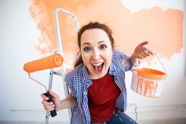 Funny smiling woman painting interior wall of new house. Redecoration, renovation, apartment repair and refreshment concept. — Stock Photo, Image