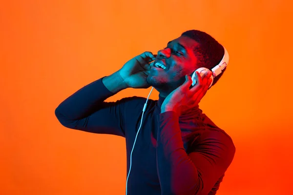 Νεαροί αφροαμερικάνοι που ακούνε μουσική με ακουστικά σε νέον φως. Ανδρικό πορτρέτο. Έννοια των ανθρώπινων συναισθημάτων, έκφραση προσώπου, διακοπές ή Σαββατοκύριακο, χόμπι, — Φωτογραφία Αρχείου