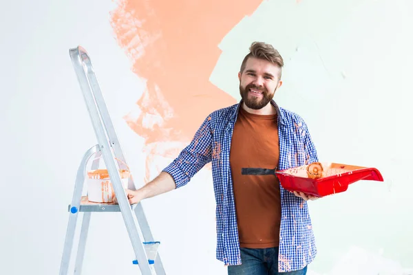 Renovation, redecoration and repair concept - Cheerful guy painting wall in new home. — Stock Photo, Image