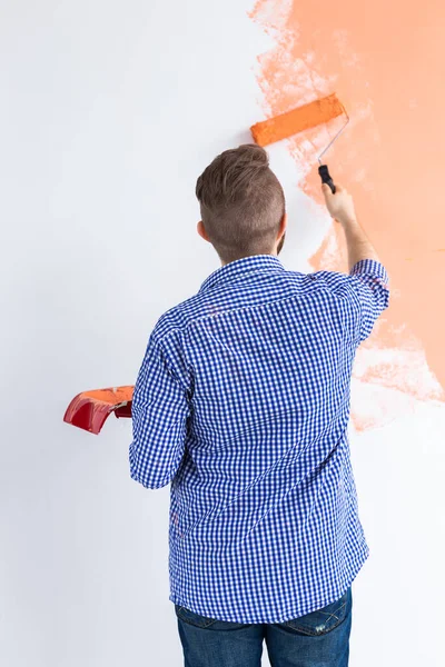 Uomo che dipinge i muri di una nuova casa. Concetto di ristrutturazione, riparazione e ridecorazione. Vista posteriore . — Foto Stock