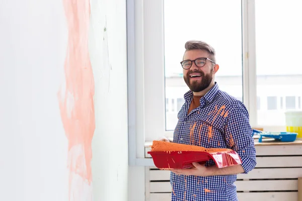 Ο άνθρωπος ζωγραφική εσωτερικό τοίχο του σπιτιού με ρολό χρώμα. Ανακαίνιση, ανακαίνιση, επισκευή διαμερισμάτων και αναψυκτικό. — Φωτογραφία Αρχείου