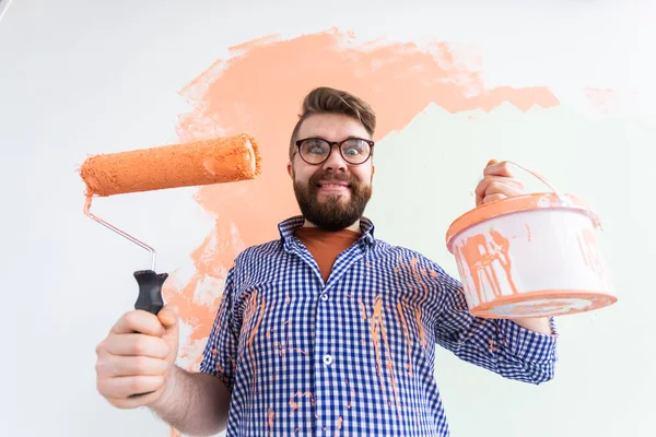 Renovation, redecoration and repair concept - Funny crazy guy painting wall in new home. — Stock Photo, Image